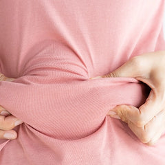 Frau im rosa T-Shirt greift Bauchspeck