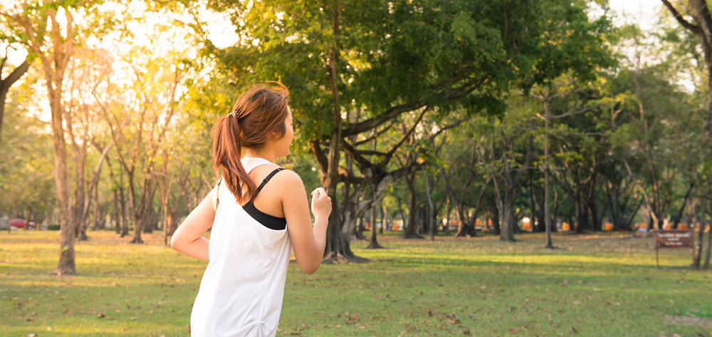 Frau in Sportklamotten im Wald joggend