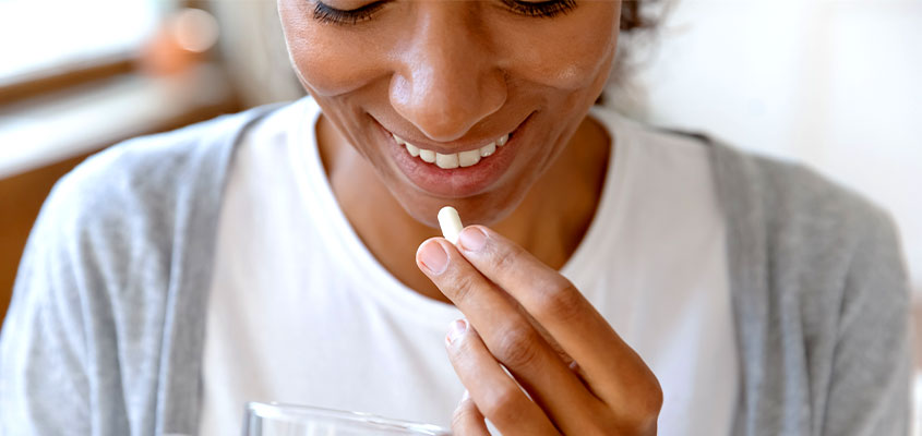Lächelnde Frau, die Synbiotika an Mund führt